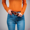 craiyon_134635_Stunningly_beautiful_woman_with_brown_hair__orange_sweater__blue_jeans__brown_belt__H.png