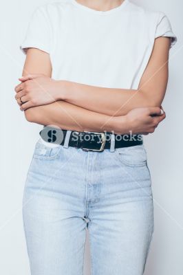 storyblocks-slender-young-woman-wearing-blue-high-waist-jeans-with-black-belt-and-white-blank-t-shirt-standing-over-plain-background-folding-hands-vertical-framing_r91PFriUX_SB_PM.jpg