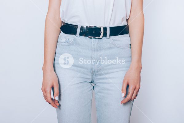 storyblocks-slender-young-woman-wearing-blue-high-waist-moms-jeans-with-belt-and-plain-t-shirt-standing-over-white-background-close-up_rVcjjBgHm_SB_PM.jpg