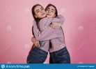 family-hugs-two-sisters-identical-wear-studio-pink-background-165456316.jpg