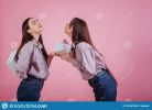 presents-each-other-two-sisters-twins-standing-posing-studio-pink-background-165767826.jpg