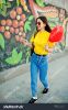 stock-photo-beautiful-teenage-walking-with-lollipop-and-heart-balloon-wear-yellow-t-shirt-jeans-near-graffiti-617363537.jpg